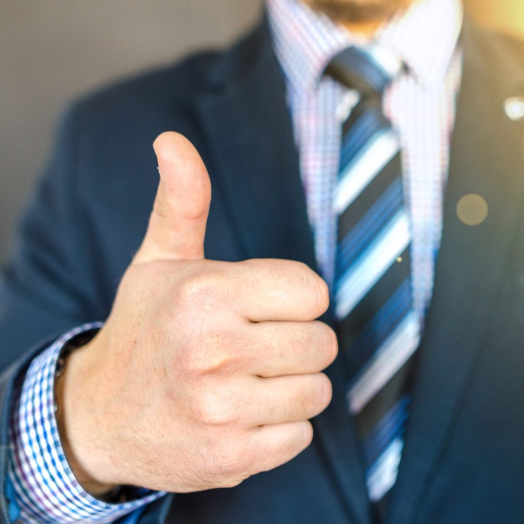 Close up photo of man wearing black suit jacket doing thumbs up gesture
